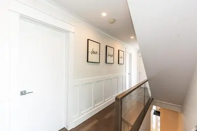 a hallway with white walls and a staircase with a door at Family friendly Lux house Near University Train Hospital in Edmonton