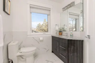 a bathroom with a toilet and a sink and a window at Family friendly Lux house Near University Train Hospital in Edmonton