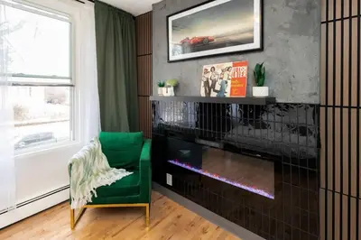 a living room with a fireplace and a green chair at Quiet & Walkable - Stampede, BMO, Nightlife & Eats in Calgary