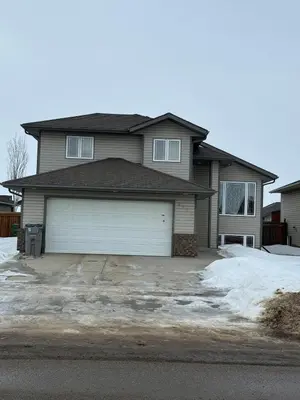 a house with a garage with snow on the driveway at Gans Home - 5 Bedroom Residence in Lloydminster