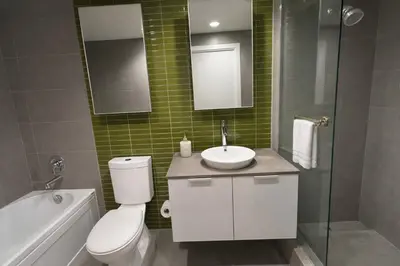 a bathroom with a toilet and a sink and a mirror at Pacific Pearl in Vancouver