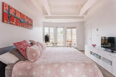 a bedroom with a large bed and a television at Private Penthouse Beside Beach with Rooftop Patio in Vancouver