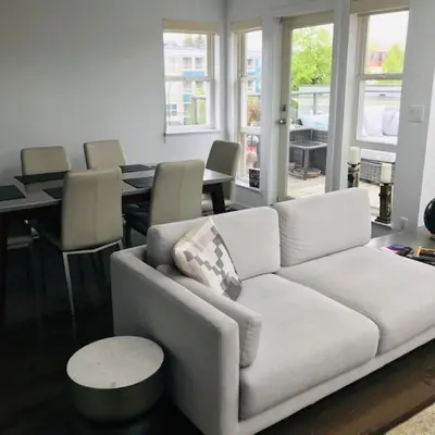 a living room with a white couch and tables and chairs at Private Penthouse Beside Beach with Rooftop Patio in Vancouver