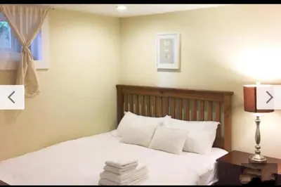 a bedroom with a bed with white sheets and a lamp at Dunbar Home in Vancouver