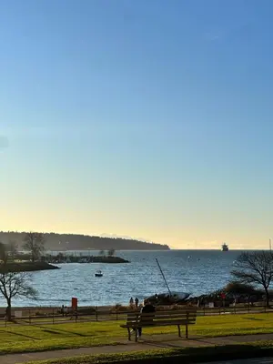 a park with a bench and a body of water at Beach House in Vancouver
