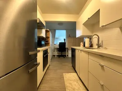 a kitchen with white cabinets and a sink and a desk at Beach House in Vancouver