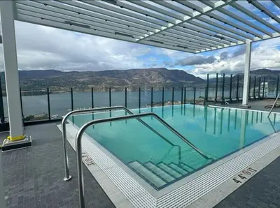 a large swimming pool with a view of the water at Signature Iconic Lakeview Downtown 2-Bedroom Loft in Kelowna