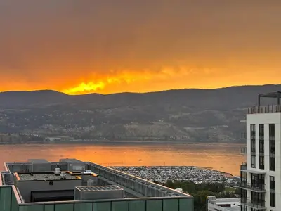 a sunset over a city and a body of water at Signature Iconic Lakeview Downtown 2-Bedroom Loft in Kelowna