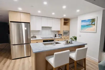 a kitchen with a stainless steel refrigerator and white cabinets at Signature Iconic Lakeview Downtown 2-Bedroom Loft in Kelowna