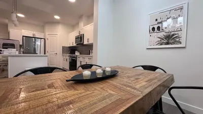 a wooden table in a room with a kitchen at Heartland Stays - Brand New 3 Bed Room Cozy Home in Cochrane