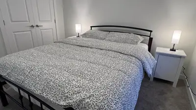 a bedroom with a bed and two lamps on tables at Heartland Stays - Brand New 3 Bed Room Cozy Home in Cochrane