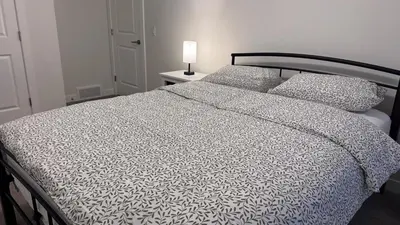 a bedroom with a bed with a white comforter and pillows at Heartland Stays - Brand New 3 Bed Room Cozy Home in Cochrane