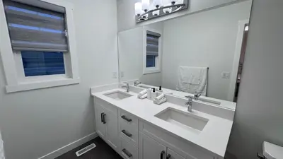 a bathroom with two sinks and a large mirror at Heartland Stays - Brand New 3 Bed Room Cozy Home in Cochrane