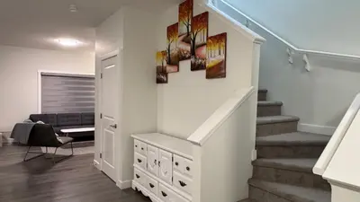 a staircase in a living room with a stair case at Heartland Stays - Brand New 3 Bed Room Cozy Home in Cochrane