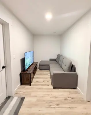 a living room with a couch and a flat screen tv at Private 1BR Suite with Kitchen, Laundry, Parking & 1 Gigabit Internet in Whitehorse