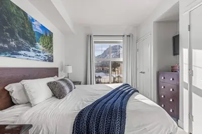 a bedroom with a large bed and a window at Serene 2BR Hideaway Hot Tub and Breathtaking Views in Canmore