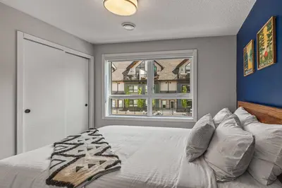 a bedroom with a large bed and a window at 3BR Canmore Haven w/ BBQ and free parking in Canmore