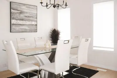 a dining room with a glass table and white chairs at 4-Level Split Home in Southeast Edmonton in Edmonton