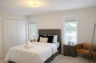 a bedroom with a bed and a chair and windows at 4-Level Split Home in Southeast Edmonton in Edmonton