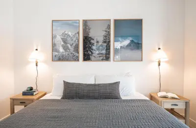 a bedroom with a bed with four pictures on the wall at Ridgeline Penthouse by Revelstoke Vacations in Revelstoke