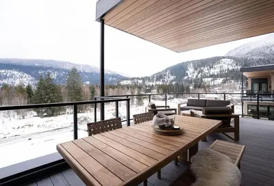 a wooden table on a balcony with a view of the mountains at Ridgeline Penthouse by Revelstoke Vacations in Revelstoke