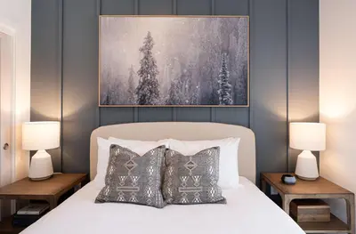 a bedroom with a bed with two lamps and a painting at Powder and Par Penthouse by Revelstoke Vacations in Revelstoke