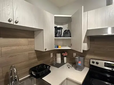 a kitchen with white cabinets and a sink and a stove at Stylish Open Cozy & Contemporary Living Space in Prince George