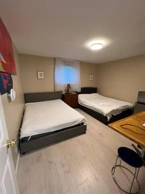 a room with two beds and a table and a desk at Brentwood Home in Burnaby