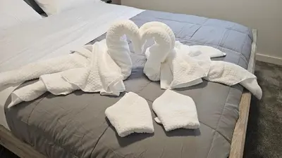a bed with white towels and swans on it at 3 Bedroom Modern Luxury House - Family Friendly, 3 Queen Beds, Free Wi-Fi, and Free Parking in Calgary