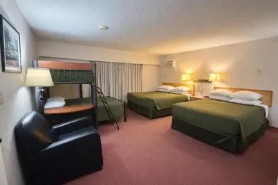 a hotel room with two beds and a chair at Rychter Hotel Hope in Hope