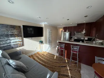 a living room with a couch and a kitchen at Cozy 2 Bdrm suite in the Heart of Renfrew Heights in Vancouver