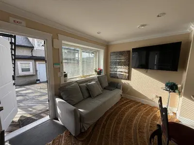 a living room with a couch and a flat screen tv at Cozy 2 Bdrm suite in the Heart of Renfrew Heights in Vancouver