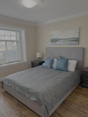 a bedroom with a large bed with blue pillows at Cozy 2 Bdrm suite in the Heart of Renfrew Heights in Vancouver