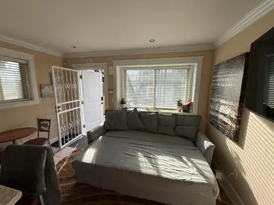 a living room with a bed and a window at Cozy 2 Bdrm suite in the Heart of Renfrew Heights in Vancouver