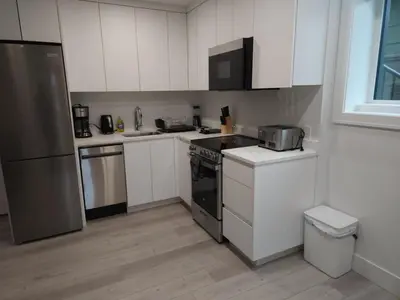 a kitchen with white cabinets and stainless steel appliances at The Rupert Split Flexible Family Living in Vancouver