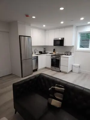 a kitchen with a black couch in the middle of it at The Rupert Split Flexible Family Living in Vancouver