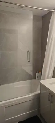 a bathroom with a shower with a white tub at UBC Area Gem Spacious 2-Bedroom Townhouse with Full Kitchen in Vancouver
