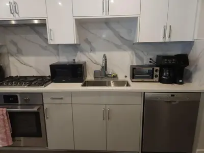 a kitchen with white cabinets and a sink and a microwave at UBC Area Gem Spacious 2-Bedroom Townhouse with Full Kitchen in Vancouver