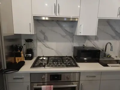 a kitchen with a stove top oven next to a microwave at UBC Area Gem Spacious 2-Bedroom Townhouse with Full Kitchen in Vancouver