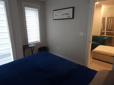 a bedroom with a bed and a chair and a mirror at UBC Area Gem Spacious 2-Bedroom Townhouse with Full Kitchen in Vancouver