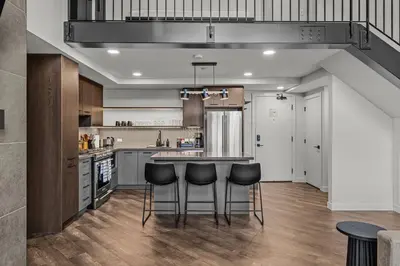 a kitchen with a counter and stools in it at Penthouse Loft| 2BD| Mountain Views| Pool + HotTub in Canmore
