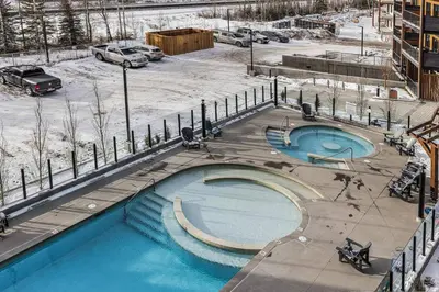a large swimming pool with snow on the ground at Penthouse Loft| 2BD| Mountain Views| Pool + HotTub in Canmore