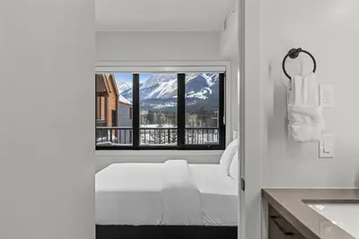 a bedroom with a bed and a view of a mountain at Premier Suite | Mountain Views | Sleeps 10 in Canmore