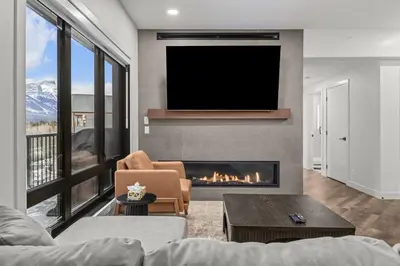 a living room with a fireplace and a tv at Premier Suite | Mountain Views | Sleeps 10 in Canmore