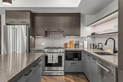 a kitchen with stainless steel appliances and wooden cabinets at Premier Suite | Mountain Views | Sleeps 10 in Canmore