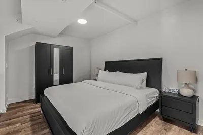 a white bedroom with a large bed and a nightstand at Premier Suite & Penthouse Loft - Sleeps 16 in Canmore