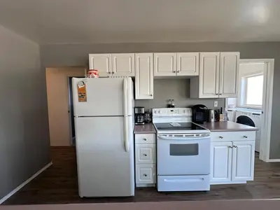 a kitchen with white cabinets and a white refrigerator at Texada Hunter Hiker friendly suite in Vananda