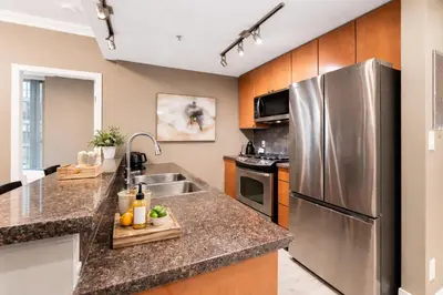 a kitchen with a stainless steel refrigerator and a sink at Bright and Comfortable 2BR Downtown Apartment for Families and Groups in Vancouver