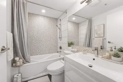 a white bathroom with a toilet and a tub and a sink at Bright and Comfortable 2BR Downtown Apartment for Families and Groups in Vancouver