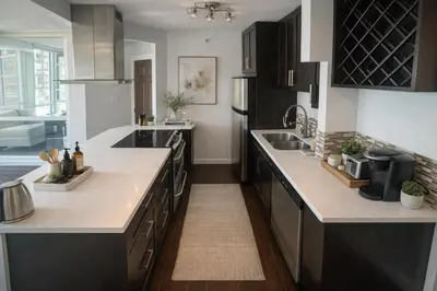 a kitchen with black cabinets and white counter tops at Elegant 2-Bedroom Condo in Vibrant Yaletown District in Vancouver